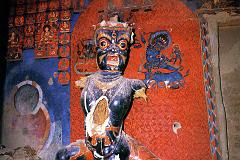 
Immediately to the right of the door is a 5m-high guardian figure, blue Vajrapani (Tib. Chana Dorje). The significantly elongated torsos, a typical Guge trademark, have been broken open, exposing the straw. This has since been closed with what looks like white plaster. To the left of Vajrapani is an empty pedestal that used to contain a statue of Tara. Photo - Weyer/Aschoff: Tsaparang, Tibets Grosses Geheimnis.
